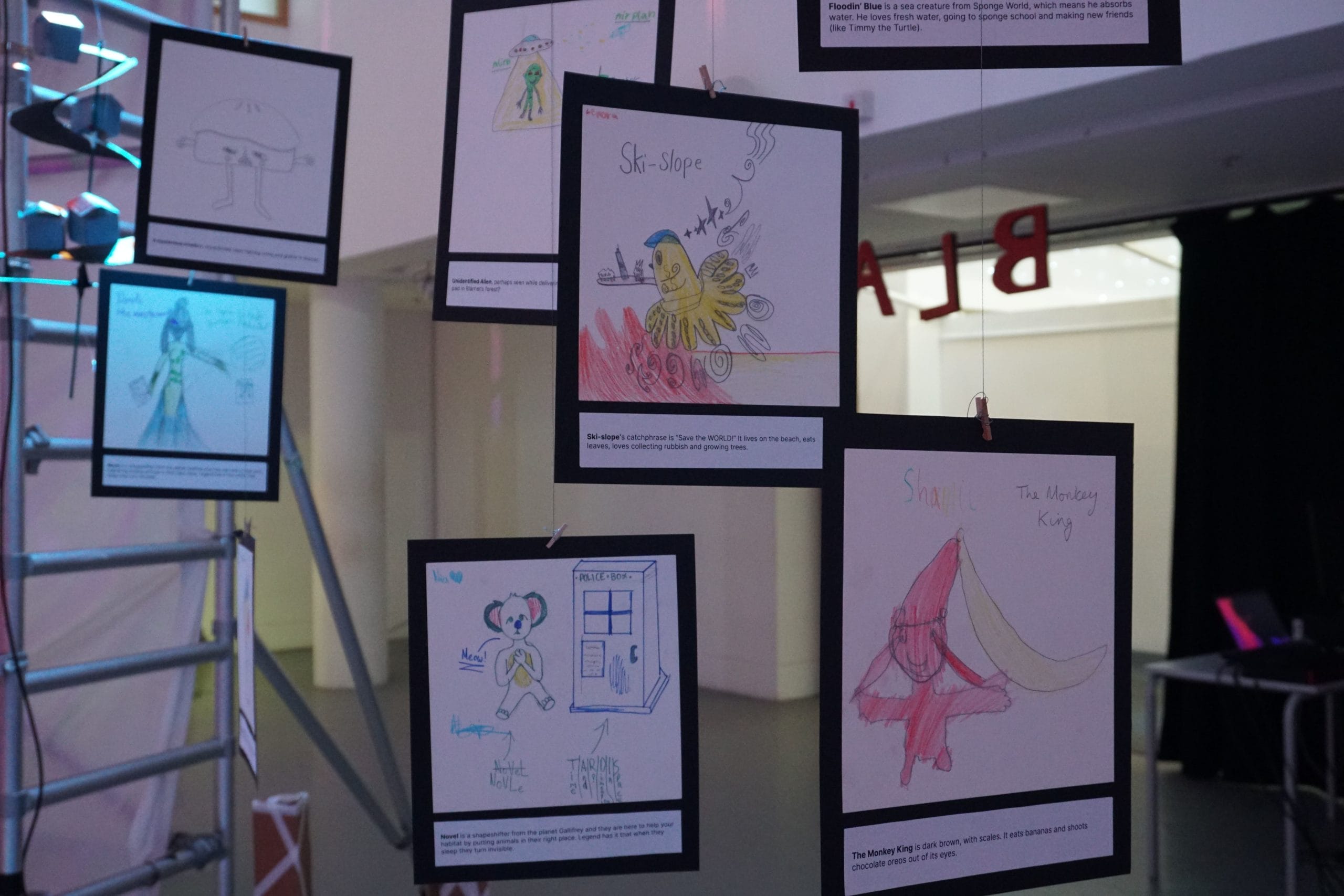 Close up of children's drawings, mounted on black cardboard. The drawings feature mythical creatures.