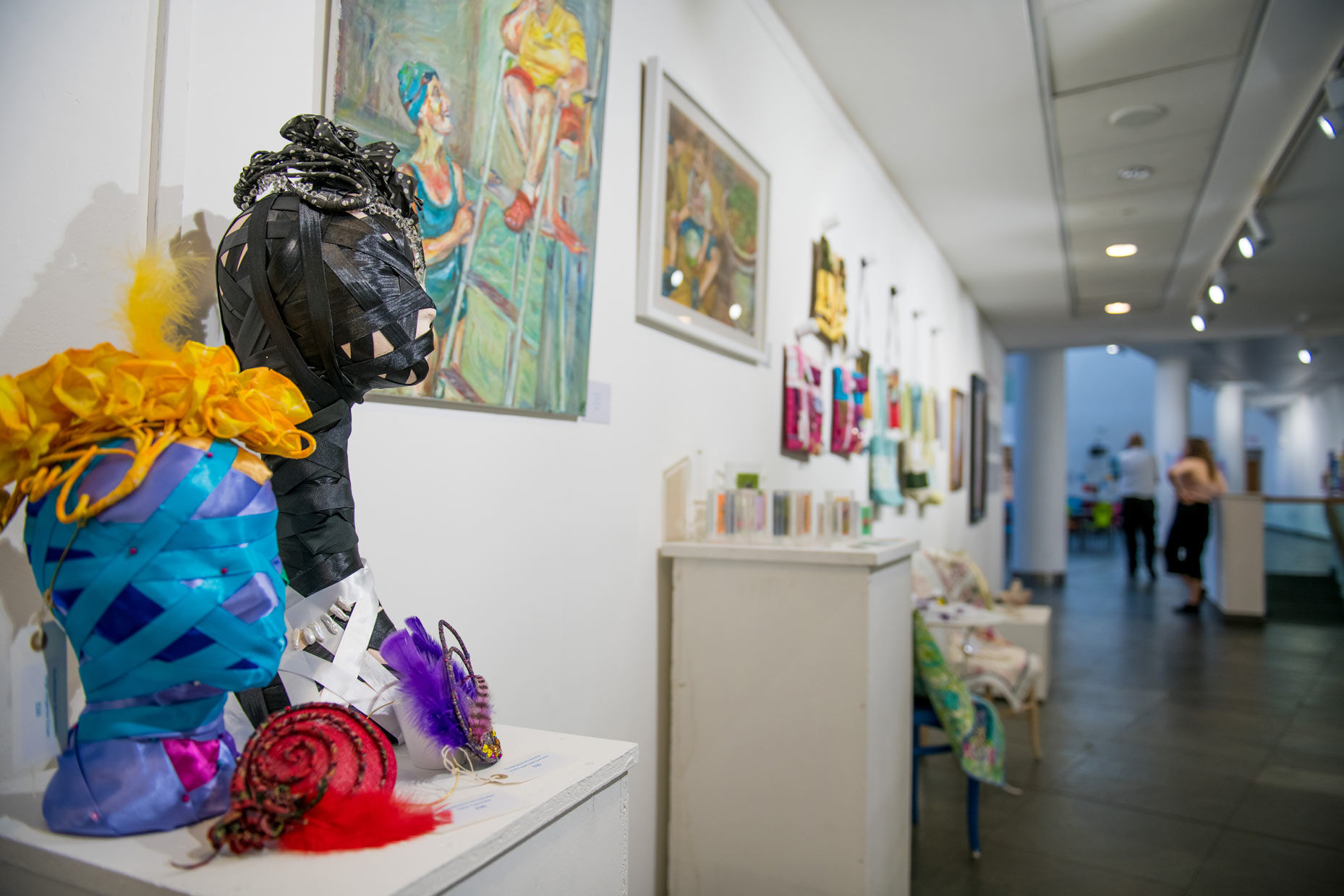 A variety of artwork on display on walls and plinths on the Exhibition Wall at artsdepot. Includes paintings and crafted items.