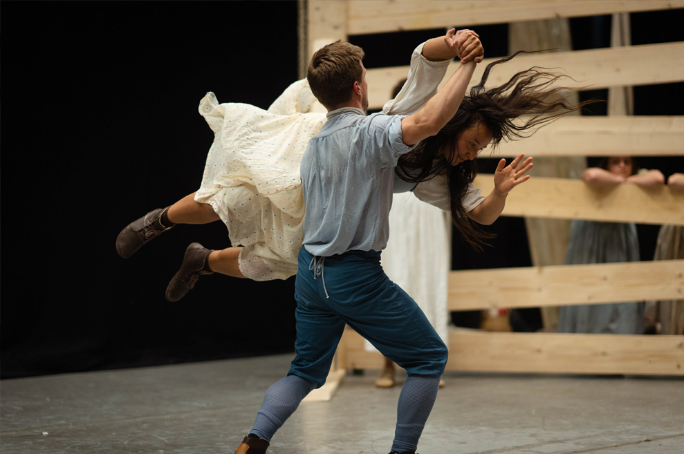 Rehearsal Photography. Action shot. Male and female performer exhibit a lift. Female performer appears to be flying, mid-air.