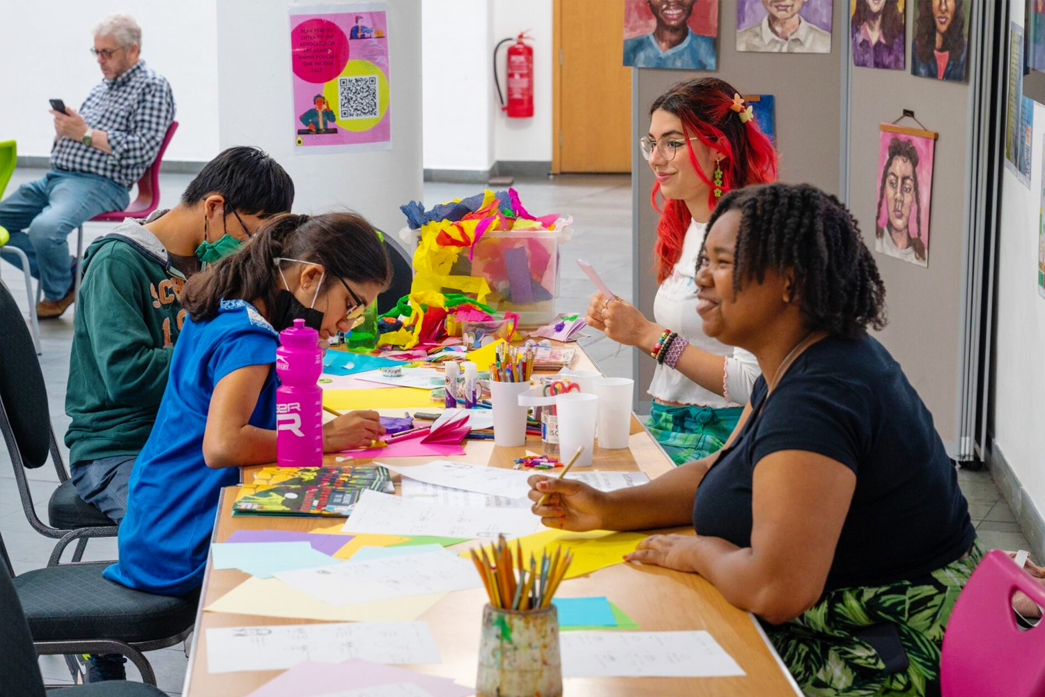 Four young people sat at a table covered in brightly coloured craft materials.