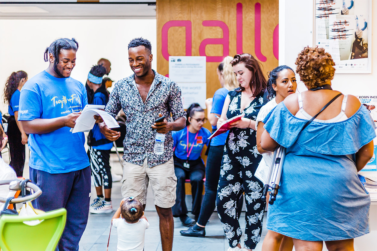 A group of adults smiling and talking at an artsdepot community event.
