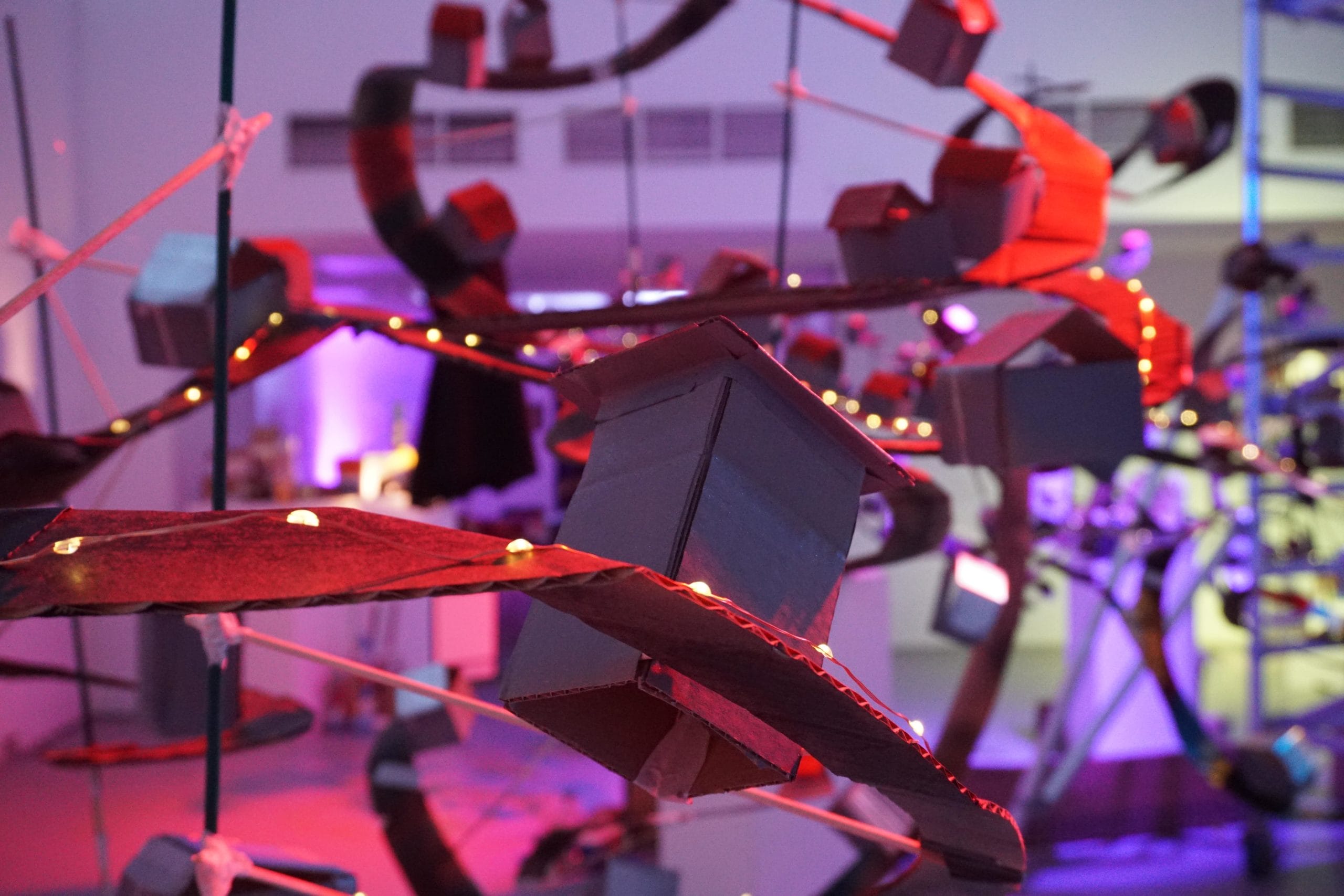 Close up of the exhibition. Spiralling cardboard roads are decorated cardboard houses and fairy lights.
